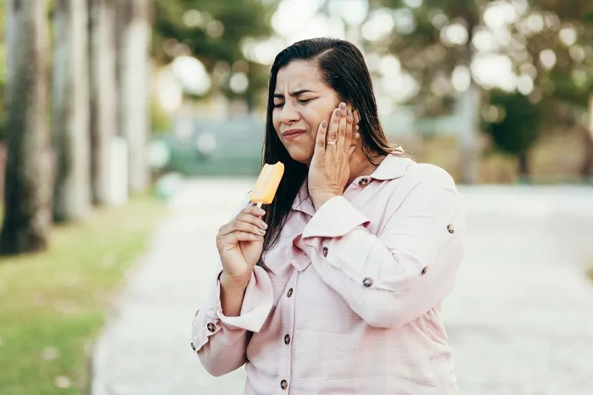 A Woman Is Feeling Tooth Sensitivity While Eating Ice Cream