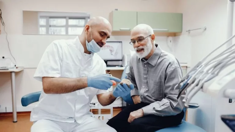 A Dentist Showing A Dental Model To A Patient