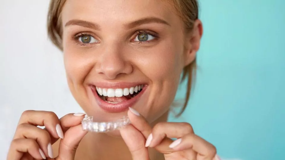 Smiling Woman Holding An Invisalign Aligner
