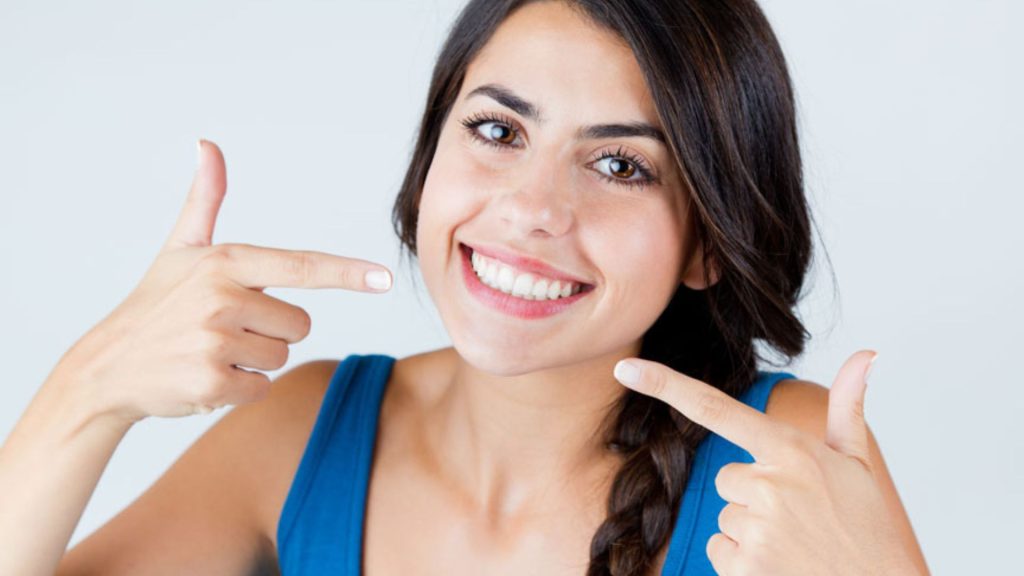 Woman Smiling and Pointing at Her Clean Teeth