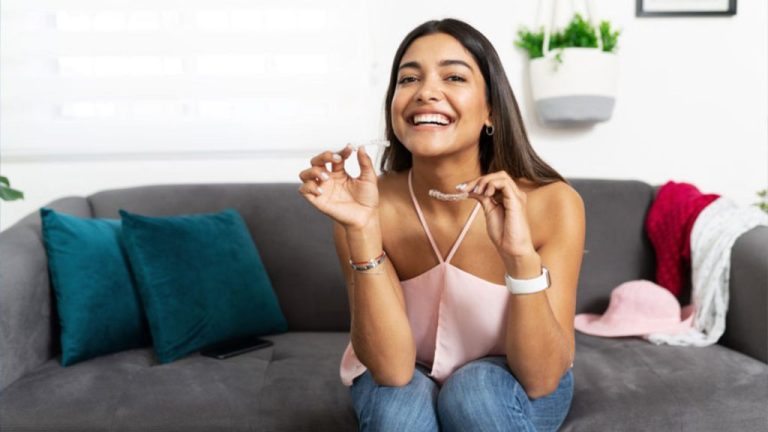 Smiling Woman Holding Clear Aligners